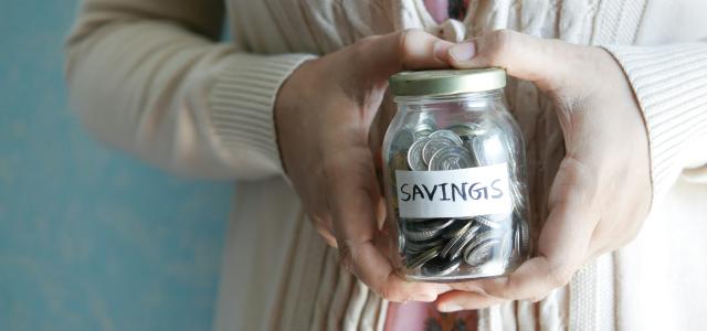 a woman holding a jar with savings written on it by Towfiqu barbhuiya courtesy of Unsplash.